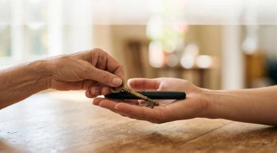 Passation symbolique d'un patrimoine familial entre générations, mains et objet précieux dans une lumière chaude